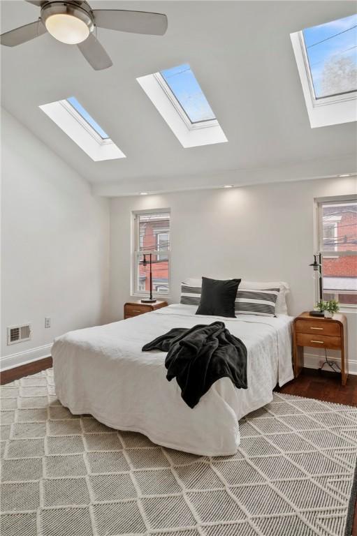 bedroom featuring lofted ceiling, ceiling fan, multiple windows, and visible vents