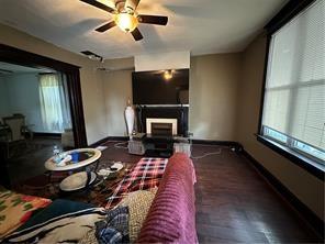 living room featuring a fireplace, a ceiling fan, and baseboards