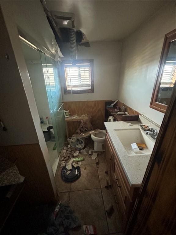 bathroom featuring toilet, a wainscoted wall, a stall shower, and vanity