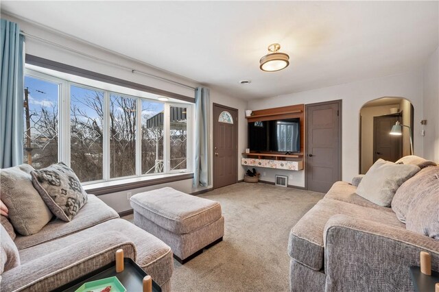 carpeted living area with arched walkways and baseboards