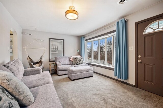 living room with arched walkways, carpet floors, visible vents, and baseboards