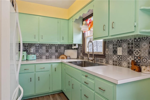 kitchen featuring light countertops, a sink, freestanding refrigerator, and decorative backsplash