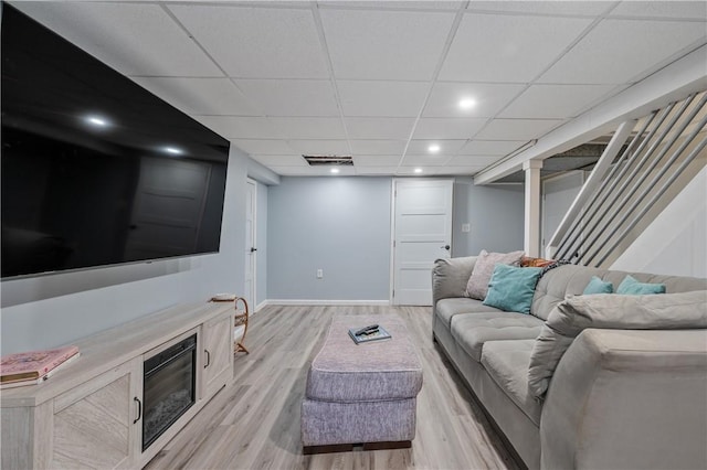 living room featuring a paneled ceiling, recessed lighting, baseboards, stairway, and light wood finished floors