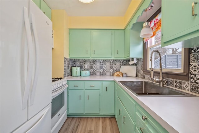 kitchen featuring white appliances, decorative backsplash, light countertops, light wood-type flooring, and a sink