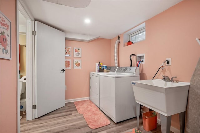 washroom with laundry area, baseboards, light wood-style flooring, independent washer and dryer, and a sink