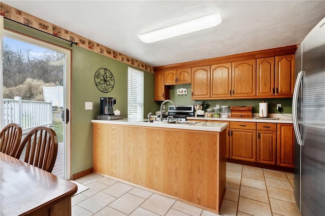 kitchen with a peninsula, plenty of natural light, light countertops, and freestanding refrigerator