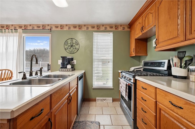 kitchen featuring a sink, visible vents, light countertops, appliances with stainless steel finishes, and brown cabinetry