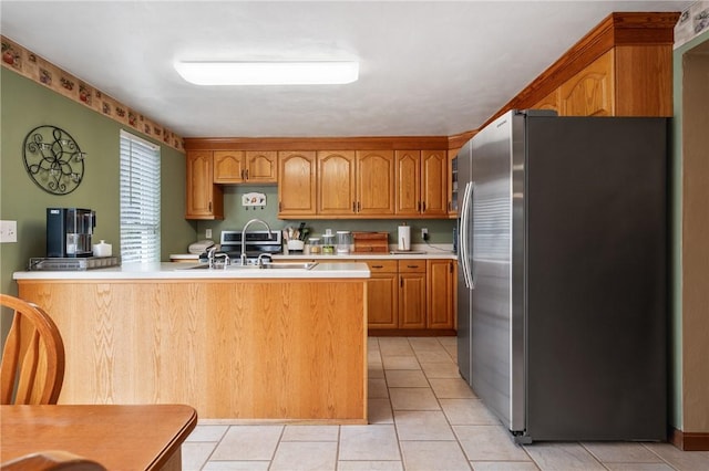 kitchen with light tile patterned floors, light countertops, stainless steel refrigerator with ice dispenser, and a sink