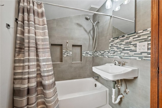 bathroom with a sink, decorative backsplash, and shower / tub combo with curtain