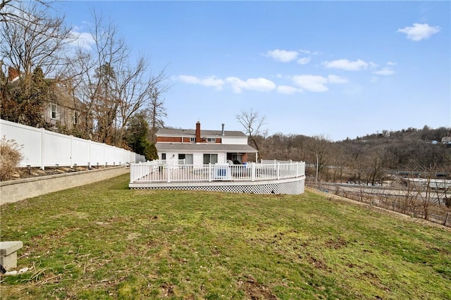 rear view of property featuring a lawn, a wooden deck, and a fenced backyard