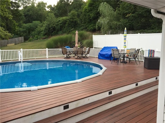 view of swimming pool featuring a fenced in pool, outdoor dining space, fence, and a deck