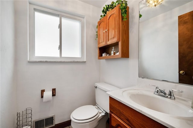 bathroom featuring toilet, vanity, and visible vents