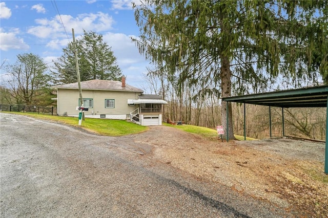 exterior space with dirt driveway, a chimney, and a yard