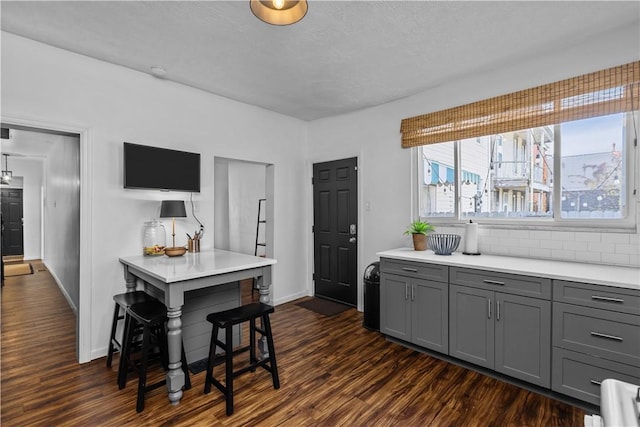 kitchen featuring dark wood-style floors, light countertops, decorative backsplash, and gray cabinetry