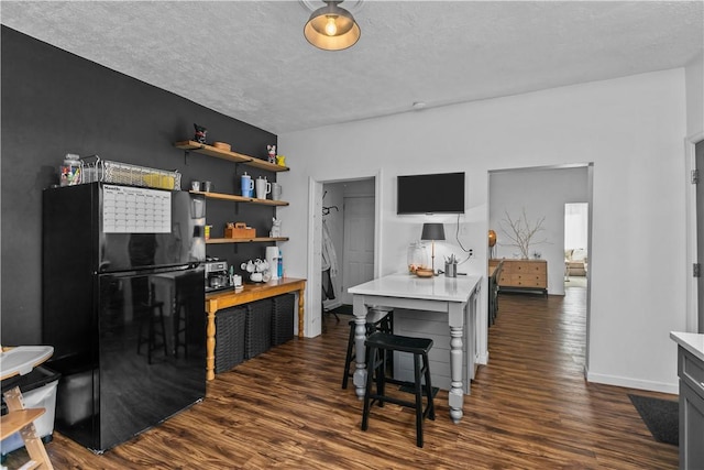 kitchen featuring freestanding refrigerator, light countertops, dark wood finished floors, and open shelves