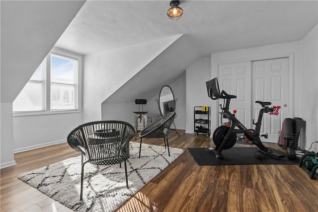 exercise room featuring vaulted ceiling, baseboards, and wood finished floors