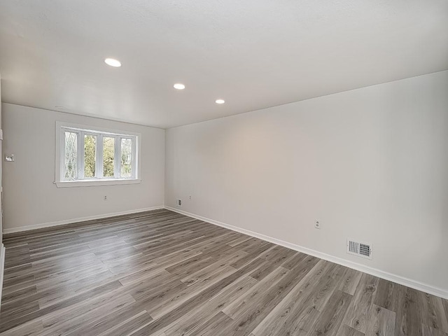 spare room with baseboards, visible vents, wood finished floors, and recessed lighting