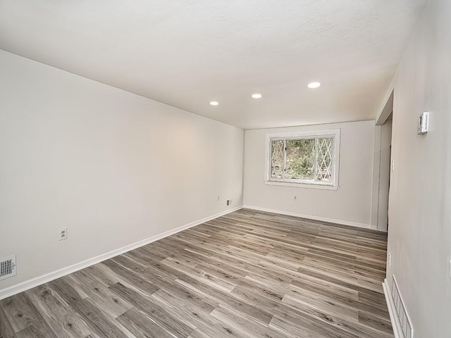 empty room featuring visible vents, baseboards, wood finished floors, and recessed lighting