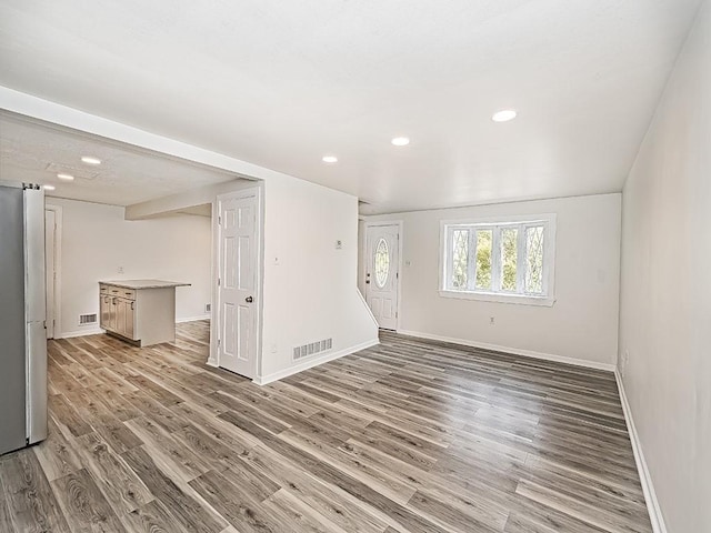 interior space featuring light wood-type flooring, visible vents, and baseboards