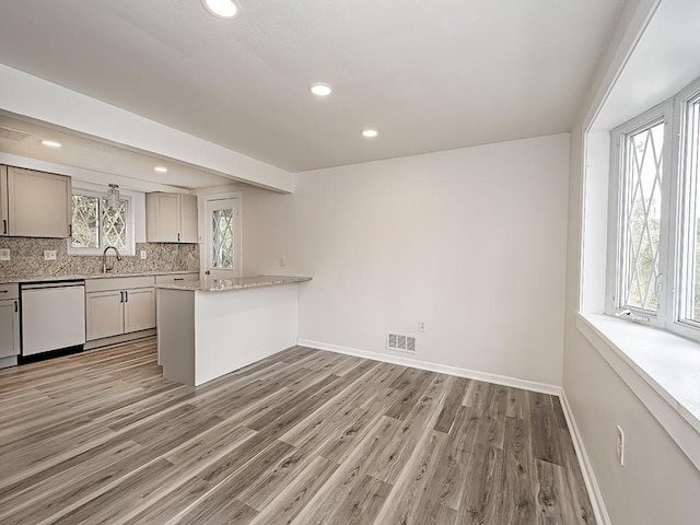 kitchen with visible vents, decorative backsplash, baseboards, dishwashing machine, and light wood-style flooring