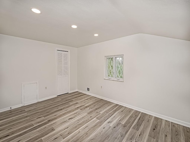 spare room with recessed lighting, lofted ceiling, visible vents, wood finished floors, and baseboards