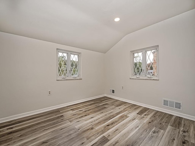 empty room featuring a wealth of natural light, lofted ceiling, and visible vents