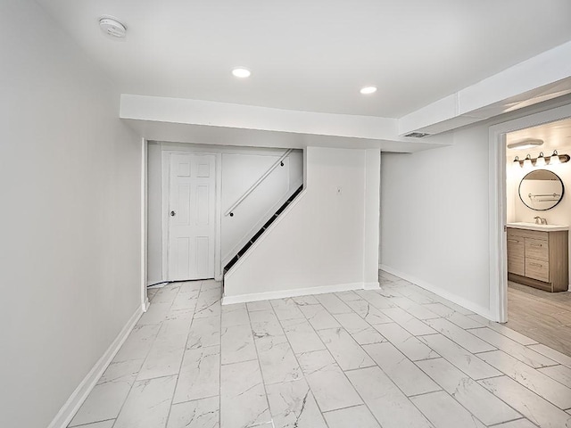 finished below grade area with recessed lighting, marble finish floor, a sink, and baseboards