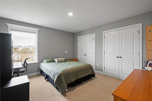 bedroom featuring multiple closets, carpet flooring, and baseboards