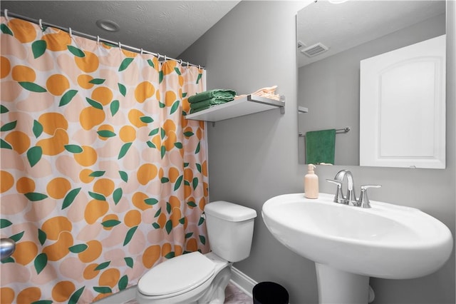 bathroom featuring visible vents, toilet, curtained shower, a textured ceiling, and a sink