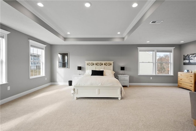 bedroom with a tray ceiling, crown molding, light colored carpet, visible vents, and baseboards