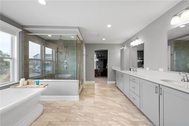 full bathroom with double vanity, a stall shower, a soaking tub, and a sink