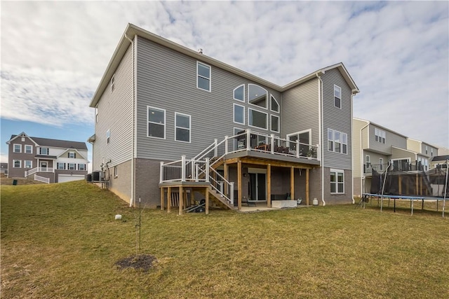 rear view of house featuring central AC unit, stairs, a yard, a wooden deck, and a trampoline