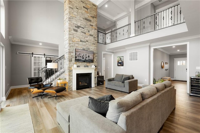 living area featuring a barn door, baseboards, wood finished floors, crown molding, and a fireplace