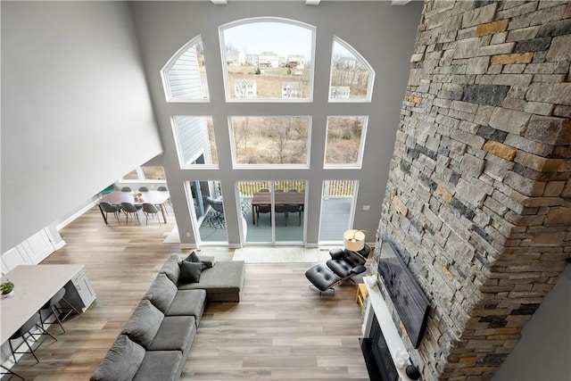 living room with wood finished floors, a high ceiling, a glass covered fireplace, and baseboards