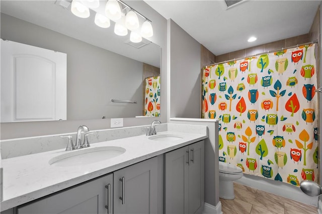 full bath featuring toilet, double vanity, visible vents, and a sink