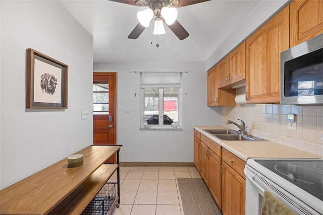 kitchen with white range with electric cooktop, light countertops, stainless steel microwave, decorative backsplash, and a sink