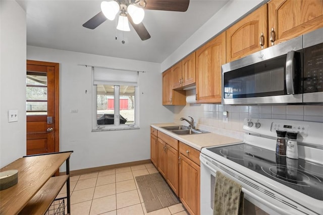 kitchen with light countertops, stainless steel microwave, electric range, decorative backsplash, and a sink