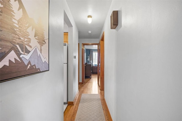 hall with baseboards and light wood-style floors