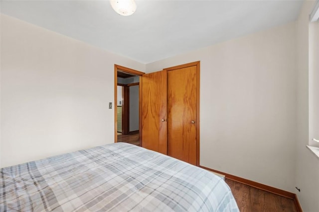 bedroom with a closet, baseboards, and wood finished floors