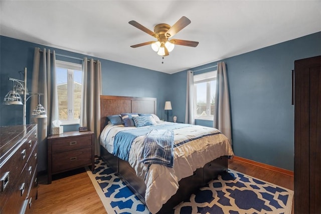 bedroom with light wood finished floors, multiple windows, and baseboards