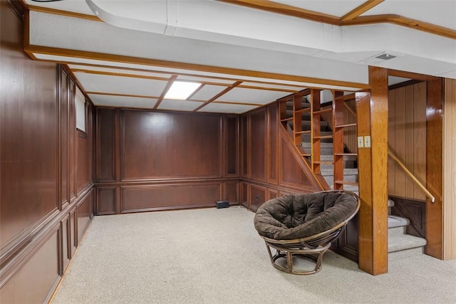 finished basement featuring light colored carpet, wood walls, and stairway