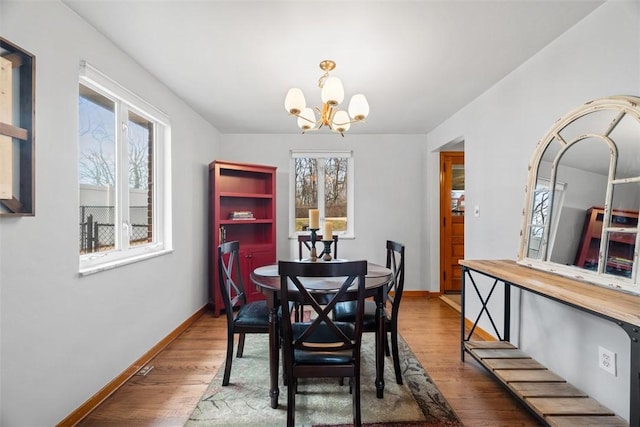 dining area featuring a chandelier, baseboards, and wood finished floors