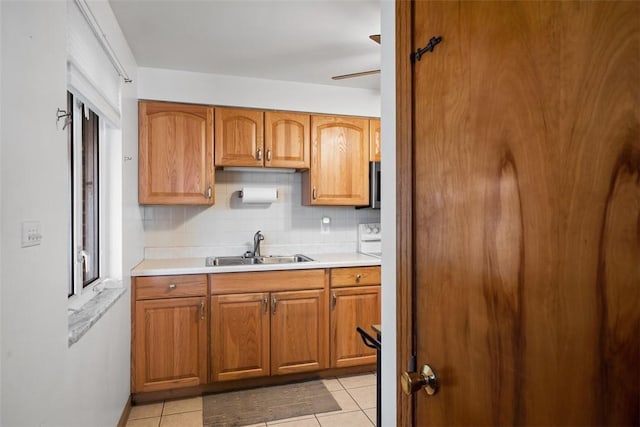 kitchen with light tile patterned floors, tasteful backsplash, light countertops, and a sink