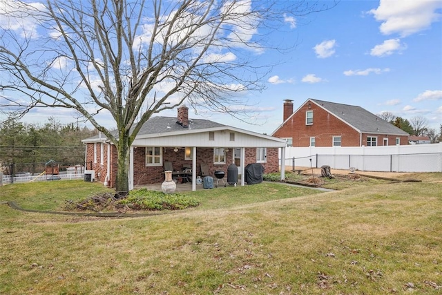 rear view of house featuring brick siding, a fenced backyard, a patio area, and a yard