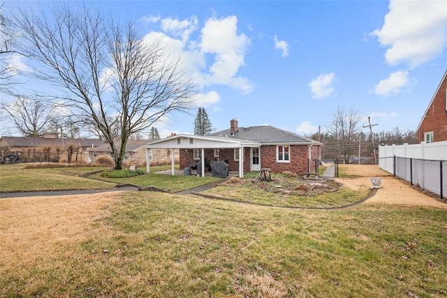 rear view of property with a yard, a fenced backyard, a chimney, and brick siding