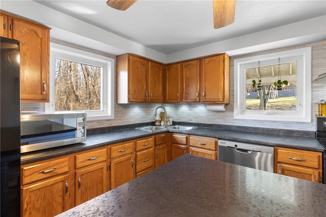 kitchen with ceiling fan, stainless steel appliances, dark countertops, and a sink