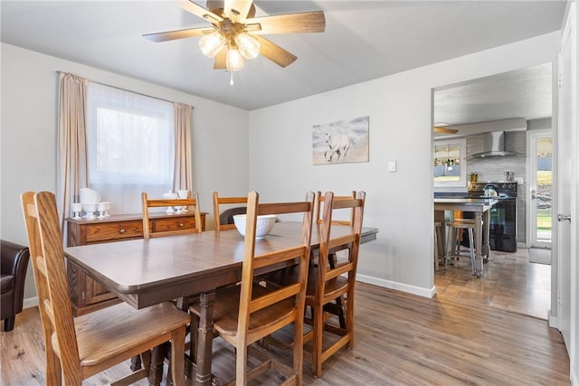 dining area with ceiling fan, baseboards, and light wood-style floors