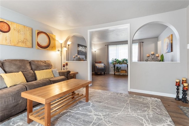 living room with baseboards, arched walkways, and wood finished floors