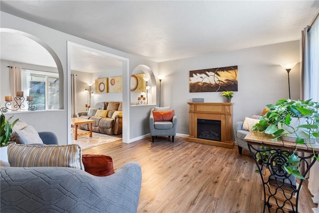 living room featuring light wood finished floors, a fireplace, and baseboards