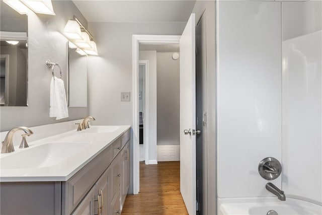 bathroom with double vanity, wood finished floors, shower / bath combination, and a sink